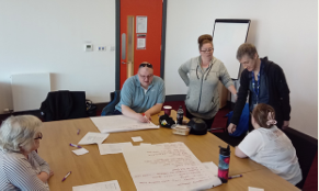 Meeting room with three people sitting and two standing up